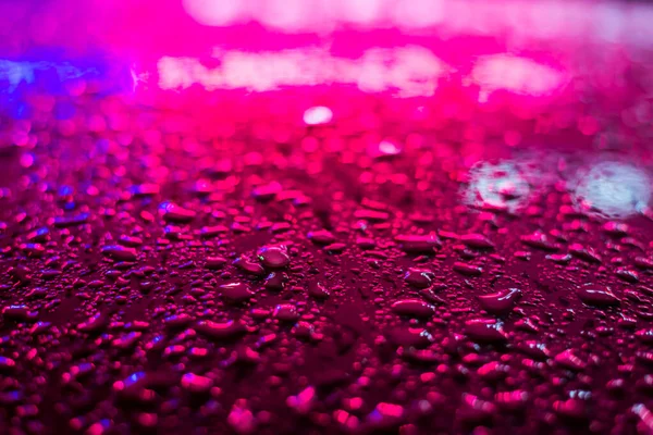 Raindrops on the metal surface in the light colored lights