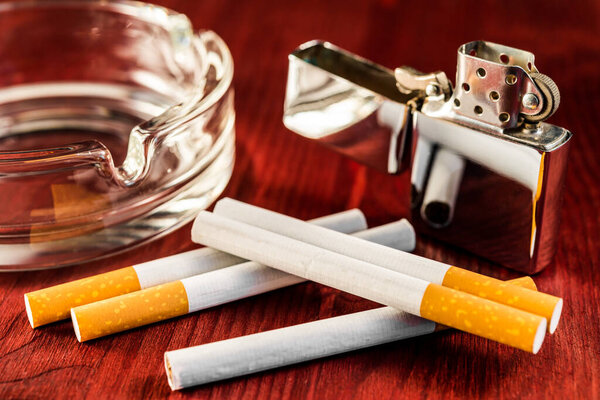 Сигареты с зажигалкой и пепельницей на столе