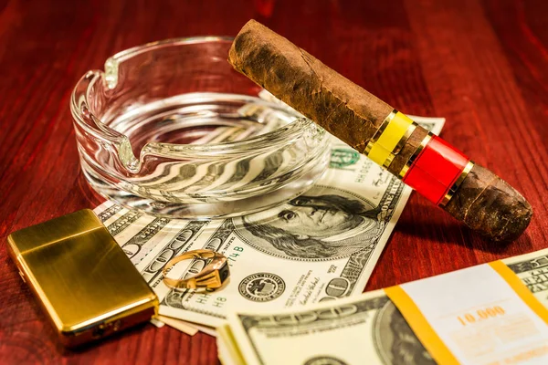 Cuban cigar with glass ashtray on a several dollar bills and als