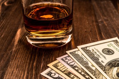 Tahta bir masada bir bardak viski ve para. Görüntüyü kapat, fo