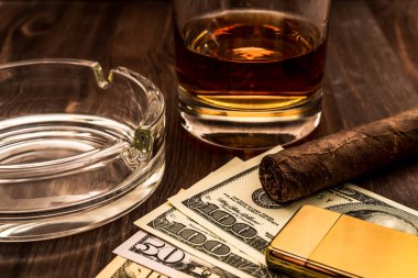 Bir bardak viski ve Küba purosu ve altın çakmağı olan bir para.