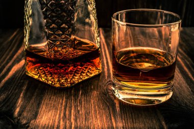 Bir kadeh viski ve ahşap bir masada bir bardak. Açı görünümü