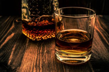 Bir kadeh viski ve ahşap bir masada bir bardak. Açı görünümü