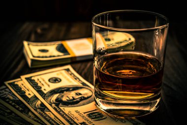 Tahta bir masanın üzerinde bir paket dolarla bir bardak viski.. 