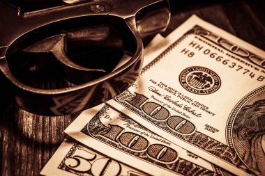 Tabanca tetikleyicisi ve para ahşap masada. Görüntüyü kapat.