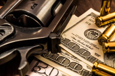 Mermili tabanca ve ahşap masanın üzerinde para. Kapat.