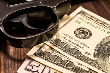 Tabanca tetikleyicisi ve para ahşap masada. Görüntüyü kapat.