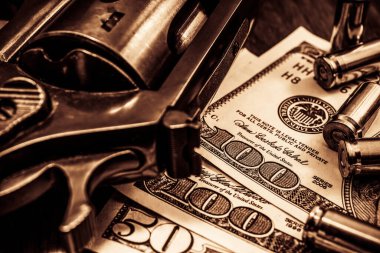 Mermili tabanca ve ahşap masanın üzerinde para. Kapat.