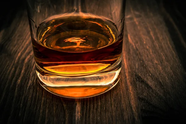 Glass of whiskey on a wooden table. Close up view