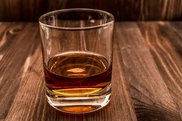 Tahta bir masada bir bardak viski. Açı görünümü