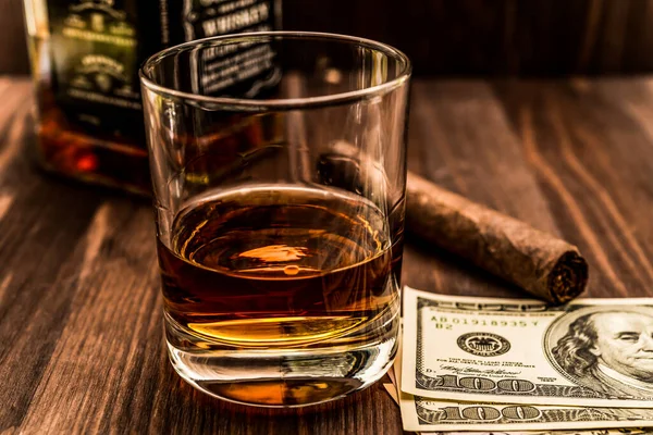 Bir şişe viski ve bir bardak Küba purosu ve para.