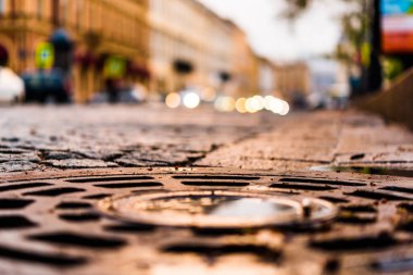 Şehir meydanı taşlarla döşenmiş, arabalar yolda.