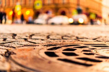 Taşla döşenmiş şehir merkezi meydanı, stree üzerinde giden araba.