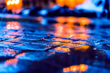 Akşam şehrinin parlak ışıkları, bir su birikintisinde yansıma