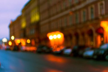 Akşam şehrinin parlak ışıkları, boş cadde. Dikkati dağılmış.