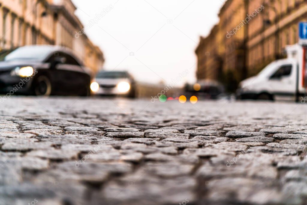 City street paved with stone, on which riding cars. View from th