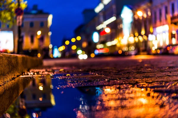 The bright lights of the evening city after rain, street with ca