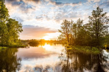 Gölün üzerinde gün batımı, adanın yakınındaki bir kayada oturan kuş, aw
