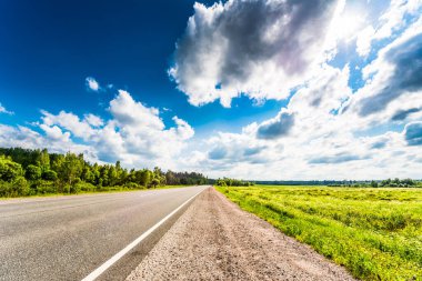 Kırsal yol tarlalardan ve ağaçlardan geçiyor.