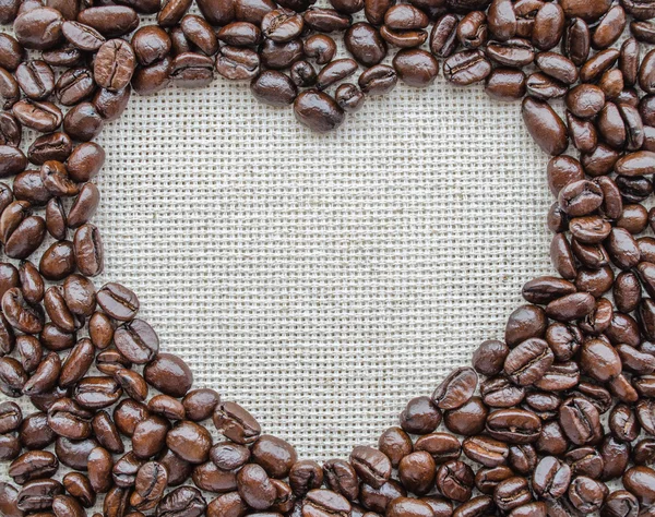 Сердце из кофейных зерен на текстурированном мешке — стоковое фото