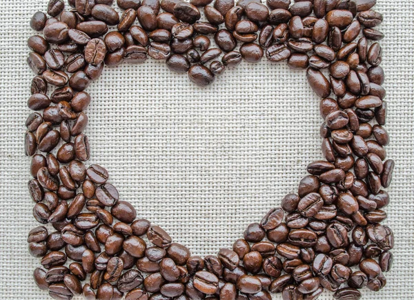 Сердце из кофейных зерен на текстурированном мешке — стоковое фото