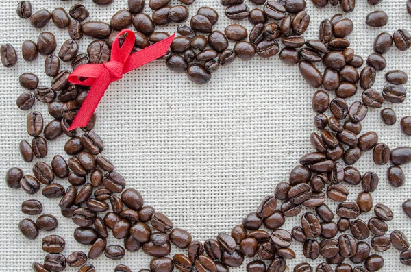 Serce się z ziaren kawy na teksturowane worek — Zdjęcie stockowe