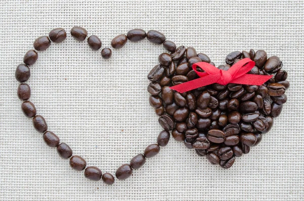 Two hearts of coffee beans on a textured bag — Stock Photo, Image