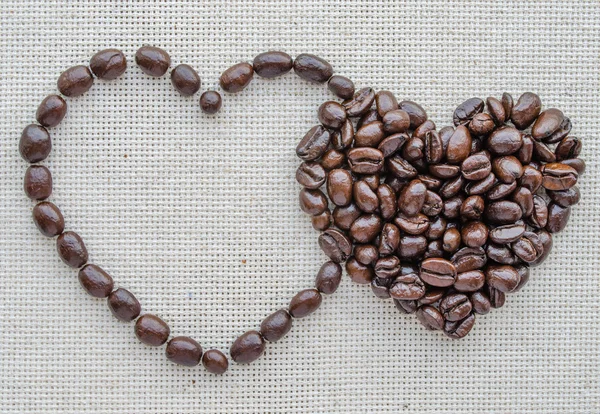 Two hearts of coffee beans on a textured bag — Stock Photo, Image