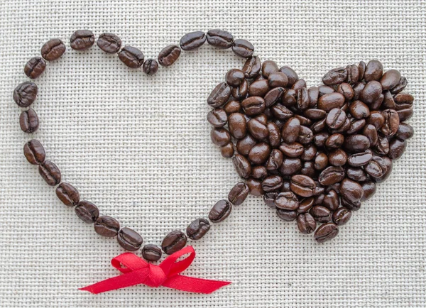 Два сердца кофейных зерен на текстурированной сумке — стоковое фото