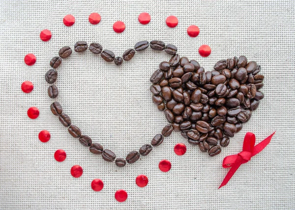 Deux cœurs de grains de café sur un sac texturé — Photo