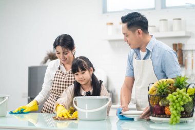 Asyalı genç bir aile kızlarına mutfak tezgahını temizlemeyi öğretiyor. Çocuk ve ailesi birlikte dans edip, eğlenerek gülümsüyorlar. Evi mutlulukla temizlerken mutlu bir aile anı..