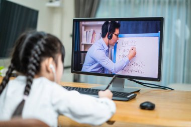 Evde eğitim gören Asyalı kız sanal video konferansından online ders alıyor. Küçük çocuk dizüstü bilgisayara bak ve evdeki öğretmenden gelen kovid19 salgınına bağlı dijital uzaktan kumanda toplantısıyla çalış..