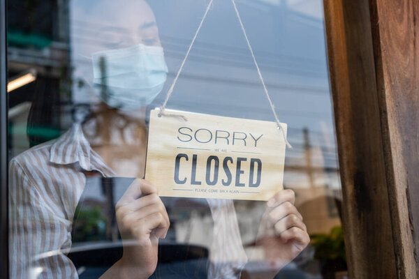 Азиатка клиентка носить маску из-за Covid-19, заказать напиток официантке на стойке кафе. Молодая девушка использовать гель для очистки и мыть руки, прежде чем получить еду на вынос от ресторанного работника