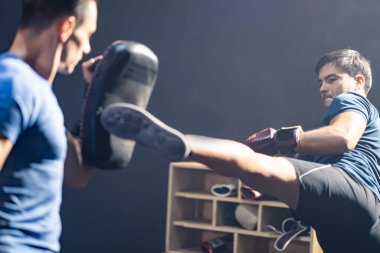 Kafkas fitness eğitmeni boks ya da Muay Thai yapan genç sporcu boksörleri eğitip motive eder. Boks eldiveni dövüşçüsü spor salonunda antrenör öğretmeniyle yumruk at ve tekmele.