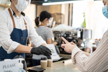 Asyalı kafe sahibi faturalar ve iş ödemeleri yüzünden hayal kırıklığına uğramış görünüyor. Depresyondaki barista çalışanı Covid19 salgını sırasında koruyucu maske takıyor. Restorandaki finansal problemden endişe ediyor..