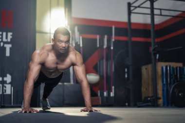 Asyalı, kaslı vücut geliştirici spor salonunda kas geliştiriyor. Aktif üstsüz, güçlü sporcu ya da sporcu spor eğitmeni karın kasları çalıştırıyor, stadyumdaki sağlık hizmetleri için yere basıyor.