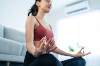 Asyalı genç, güzel, aktif bir kadın evde yoga pilates yapıyor. Spor giyim sektöründeki çekici kız mutlu ve rahatlamış hisset, evdeki oturma odasındaki çevrimiçi eğitmenin alıştırma videosunu izle.