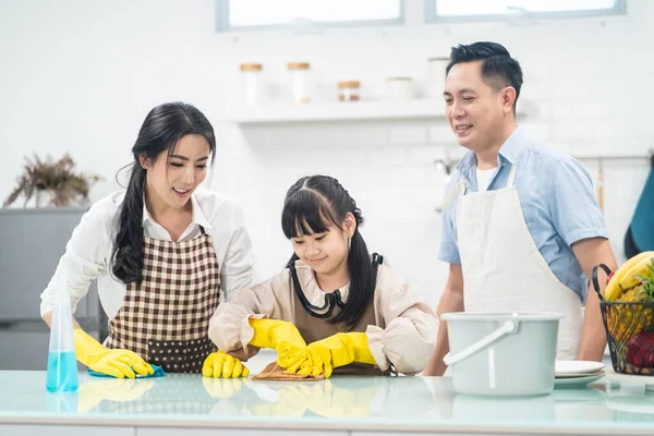 亚洲的年轻家庭教女儿打扫厨房柜台 孩子和父母一起跳舞 笑得很开心 当幸福地打扫房子时 温馨家庭的快乐时刻 — 图库照片