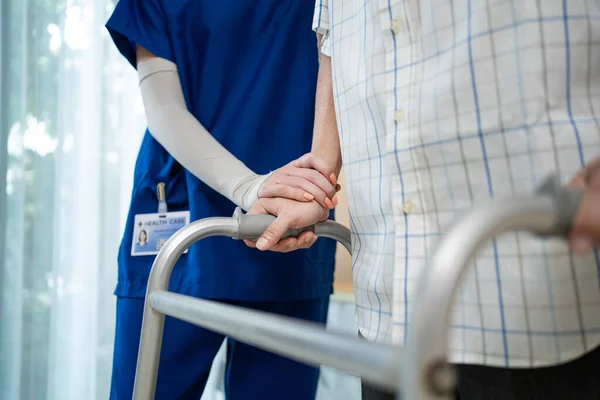 Hemşire, Walker 'la huzurevinde yürüyen adamı etkisiz hale getirmeye yardım ediyor. Bakıcı terapist doktor, yaşlı engelli hasta Zimmer çerçevesini evde kullanıyor. Tıbbi terapi sigorta konsepti.
