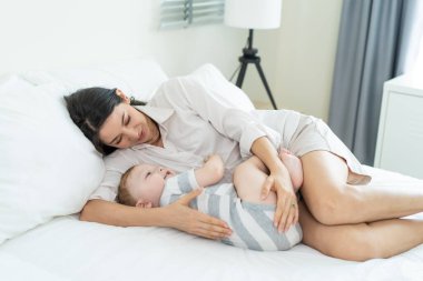 Beyaz bir anne yatak odasında tatlı bir çocukla oynaşıyor. Mutlu bir aile, çekici, şefkatli, genç bir anne, yeni yürümeye başlayan bir çocuğa sarılıyor. Oğlu, sabahları iş ilişkisinin tadını çıkarıyor..