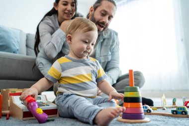 Beyaz, mutlu bir ebeveyn, bebek bebekle oturma odasında oynuyor. Çekici bir çift anne ve baba evde küçük bir çocukla vakit geçiriyor. Ev kavramında etkinlik ilişkisi.