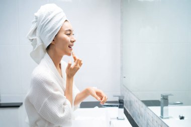 Asyalı güzel kadın yüz bakımı için yumuşak ve cilt bakımı yapıyor. Çekici kadın dokunuşları ve gençleşme için krem sürme duştan sonra nazikçe. Güzellik, cilt bakımı ve sağlık