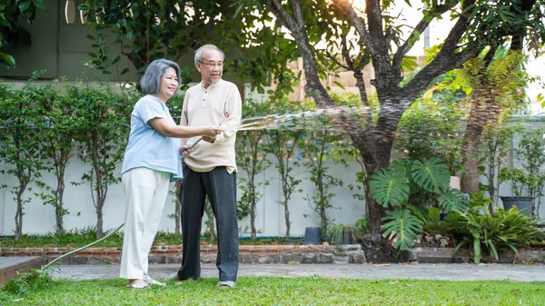 亚洲的一对老年夫妇在户外一起在家里种花 迷人的老祖父母在晚上用软管浇灌植物 老年人关系和住房概念中的活动 — 图库照片