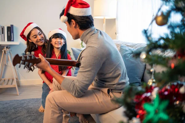 Asian lovely family member enjoy sing Christmas song together at home. Young little daughter feeling happy and excited to celebrate holiday Christmas Thankgiving party together with parents in house.