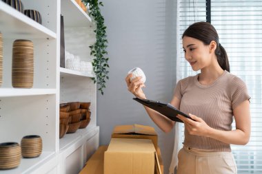 Beyaz bardaklı bir kadın modern mağazada envanter kontrolü yapıyor.