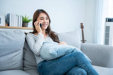 Kanepede oturmuş akıllı telefondan konuşan gülümseyen kadın.