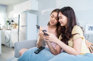 İki kadın akıllı telefonlar ve kredi kartlarıyla birlikte oturuyor.