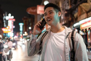 Şehrin işlek caddesinde akıllı telefondan konuşan gülen adam.