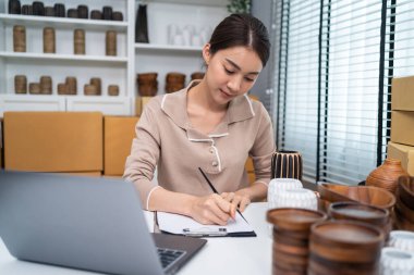 Tahta masada oturan kadın notlar yazıyor.