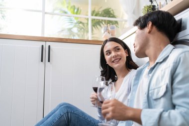 Asyalı genç evli çift evde mutfakta birlikte vakit geçiriyorlar. Çekici romantik erkek ve kadın yere oturur aile hayatını kutlamak ve yeni eve taşınmak için şarap içerler.